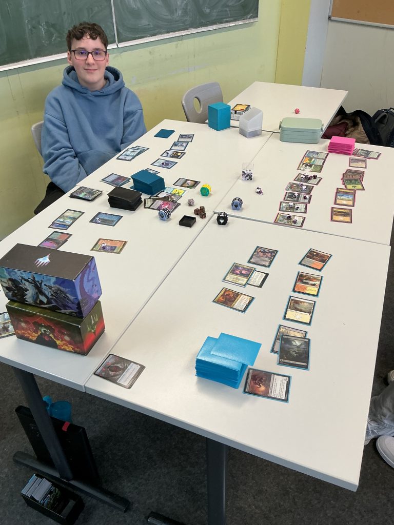 Ein Junge sitzt an einem Tisch mit vielen Magickarten